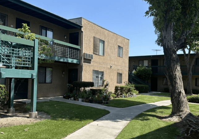 A building with a green railing and a tree in front.